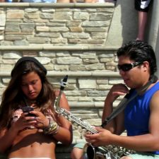 Girl texts on phone while musician plays for her