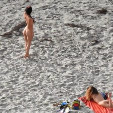 Elegant naked brunette poses on beach